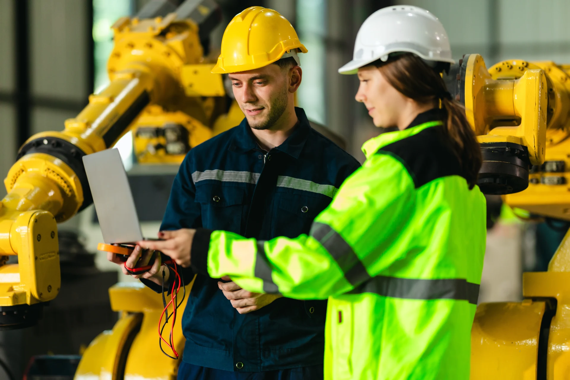 Manufacturing technicians reviewing work beside industrial robots