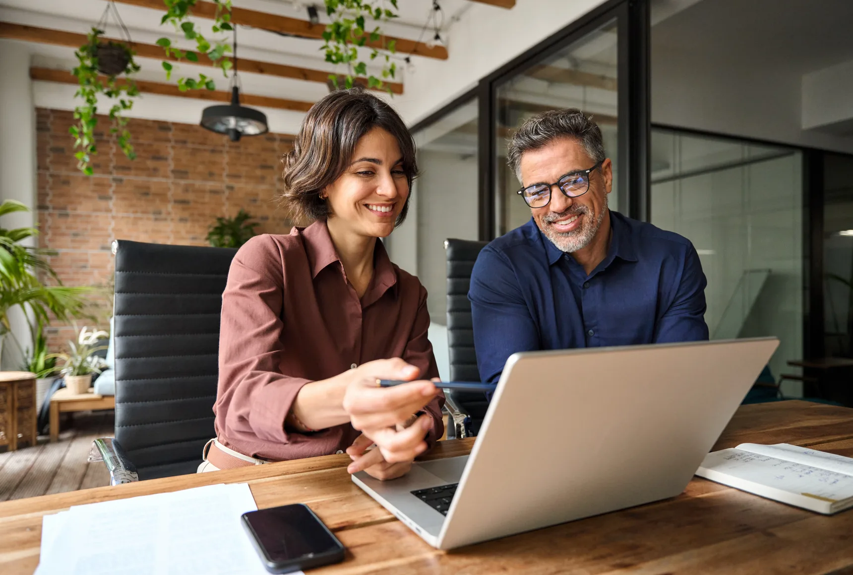 Two analysts reviewing business data at a desk with laptop